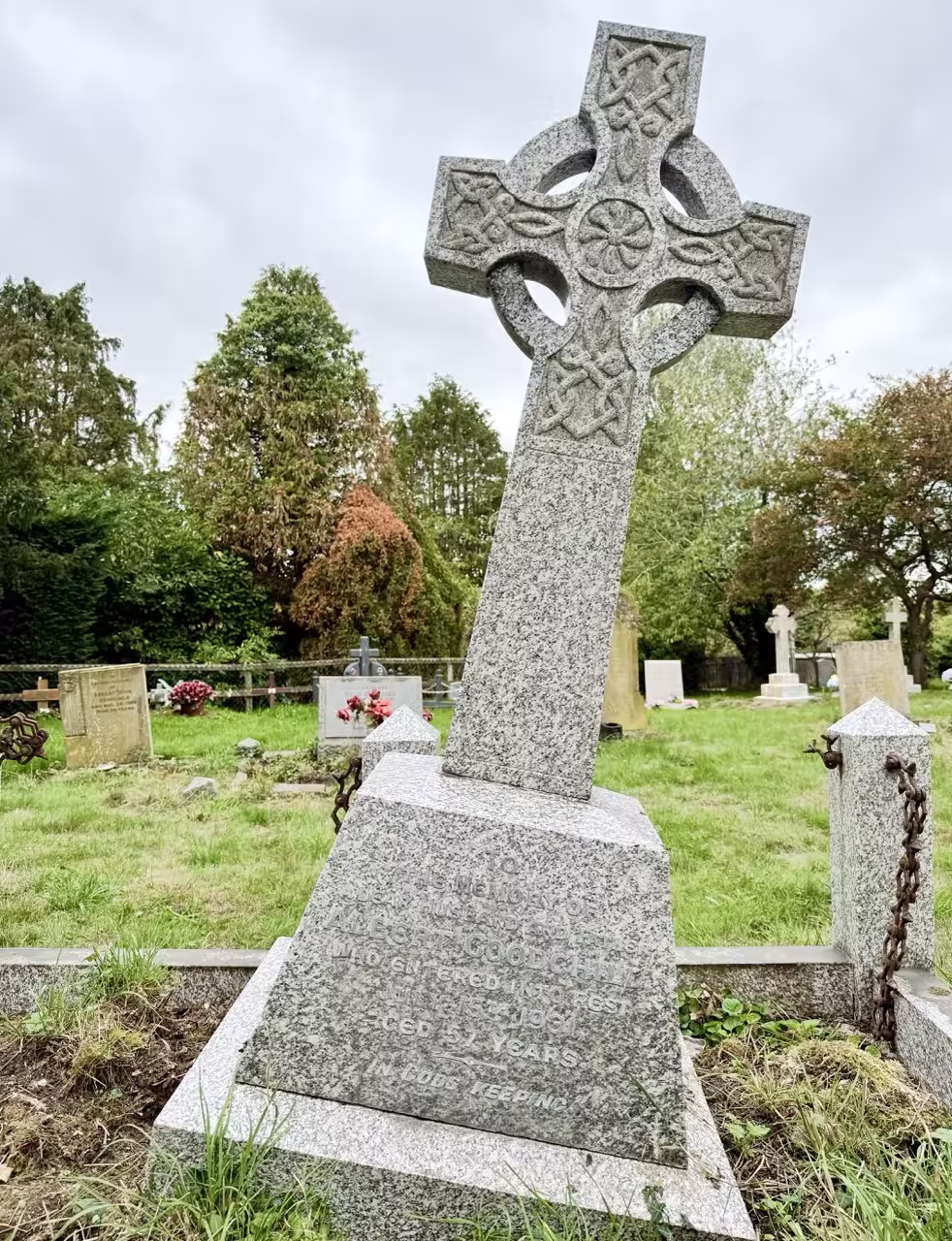 Celtic cross on base surrounded by kerbs, high posts and iron chains